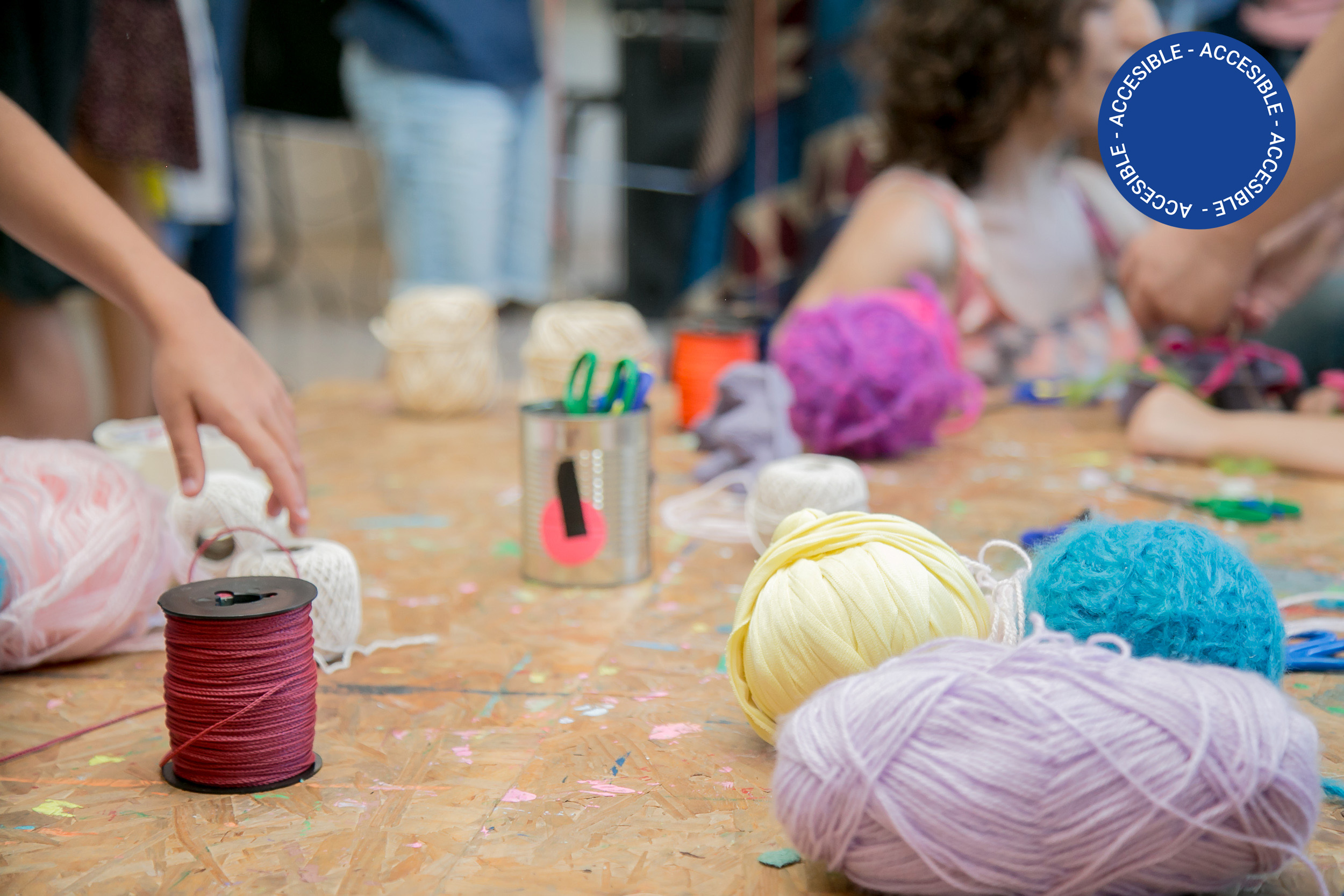 Fotografía de una mesa de taller con lanas e hilos de colores