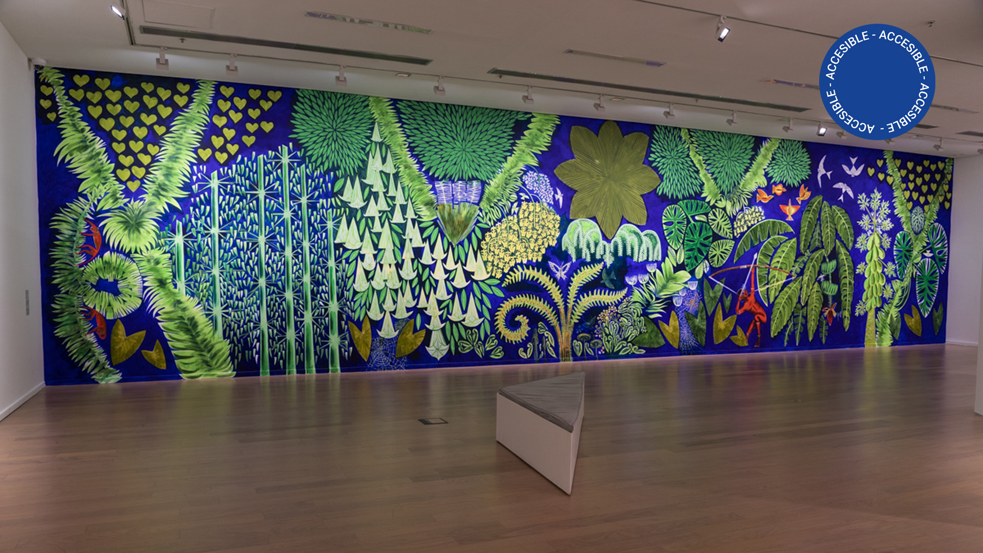 Foto de sala de la exposición Manifiesto verde. Sobre una de las paredes, puede apreciarse un gran mural de Florencia Böhtlingk, pintado con imágenes de flora y vegetación.