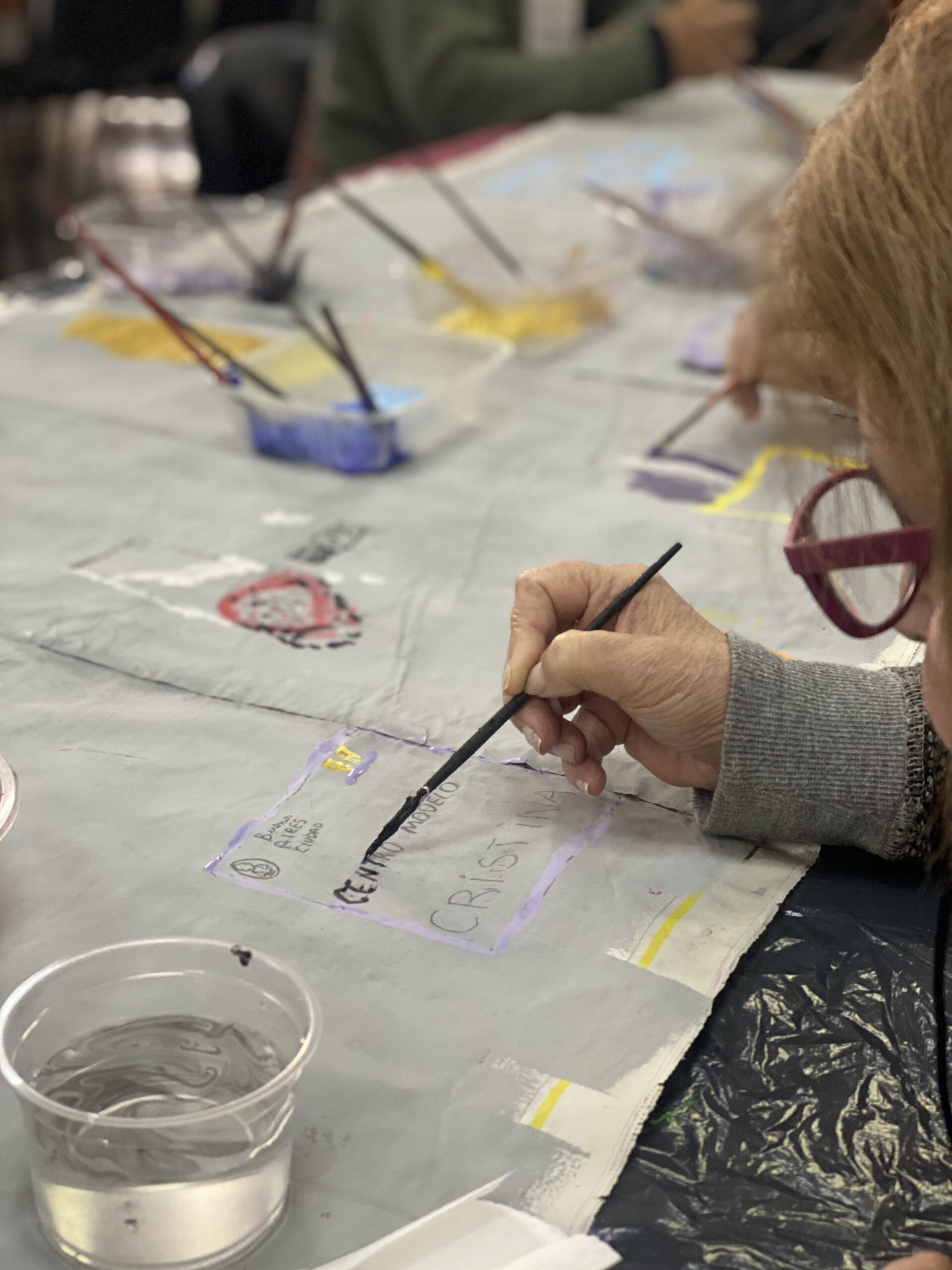 Se observa una persona mayor pintando con un pincel en uno de los talleres del moderno