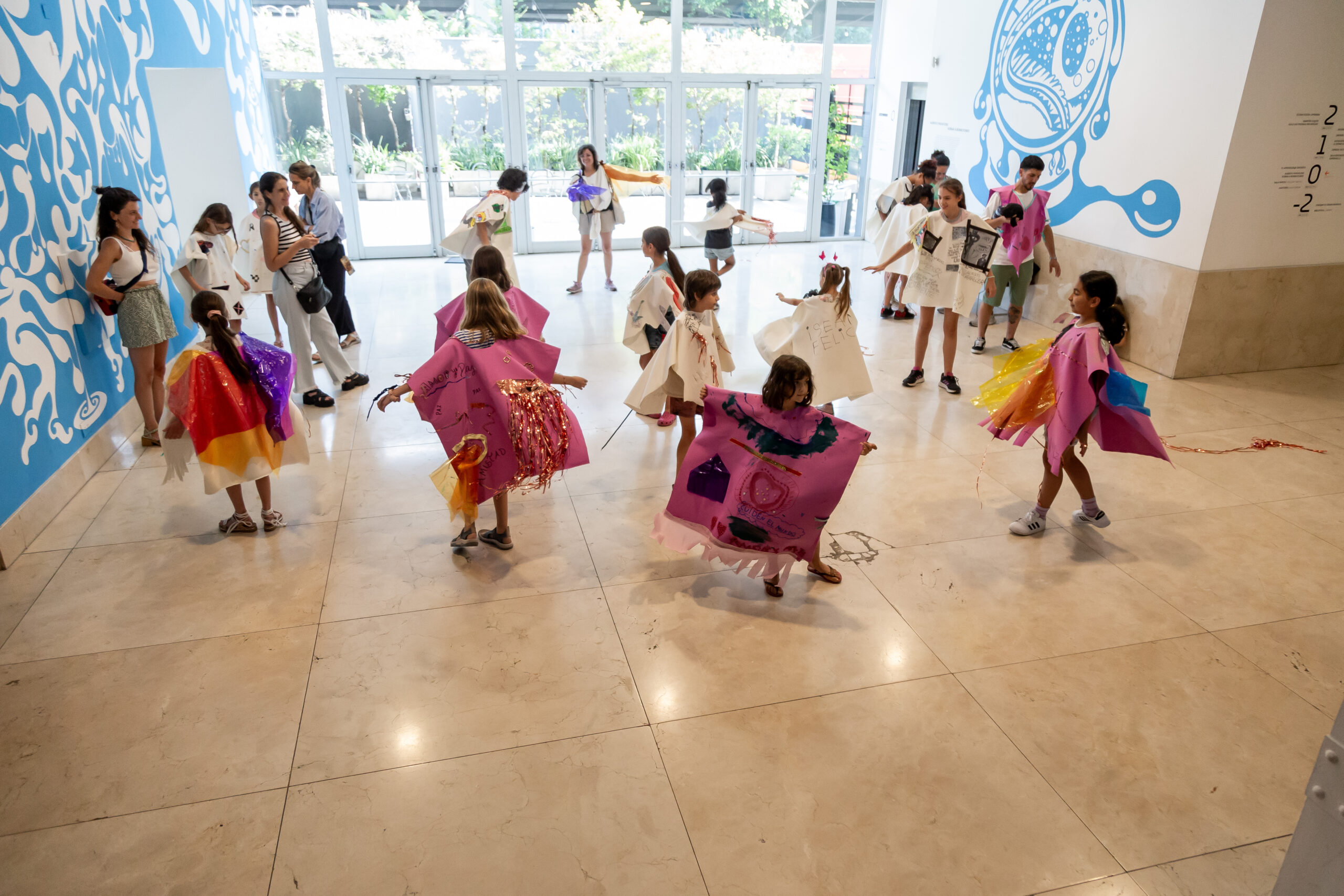 En la imagen se ve un grupo de niños y niñas en ronda participando de la actividad en el Hall del Museo Moderno.