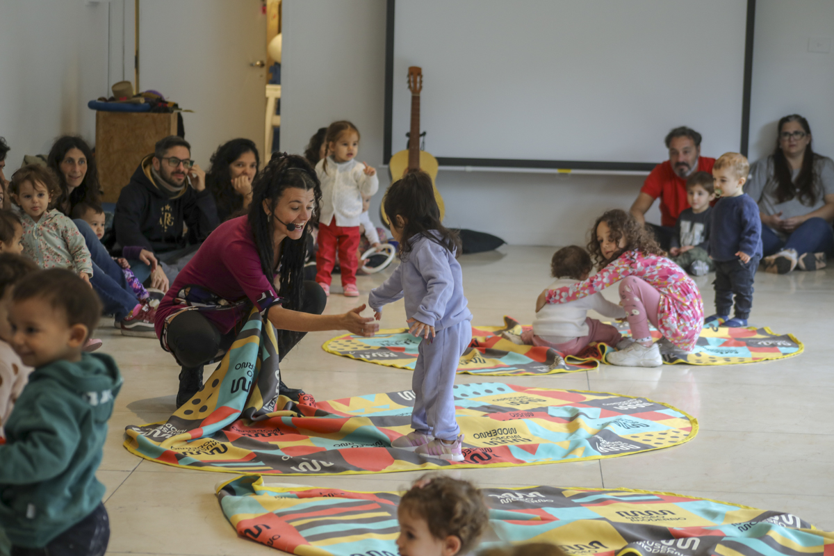 Imagen muestra una escena de juego con adultos, niños y niñas