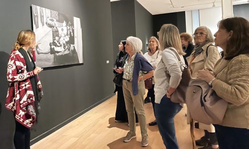 Un grupo de personas mayores mira una obra en exposición del museo mientras una de las educadoras dialoga con ellos.