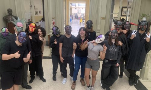 estudiantes en el pasillo de la escuela Pueyrredón posan frente a cámara con máscaras de teatro